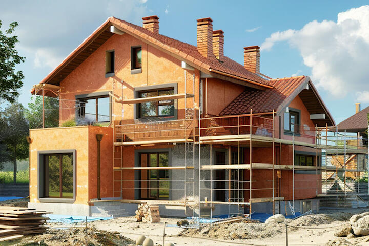 Ein Einfamilienhaus, das mit einem Gerüst versehen ist und an dem gerade gebaut wird, im Vordergrund liegen Bauschutt und Baumaterialien. Ein Einfamilienhaus, das mit einem Gerüst versehen ist und an dem gerade gebaut wird, im Vordergrund liegen Bauschutt und Baumaterialien.